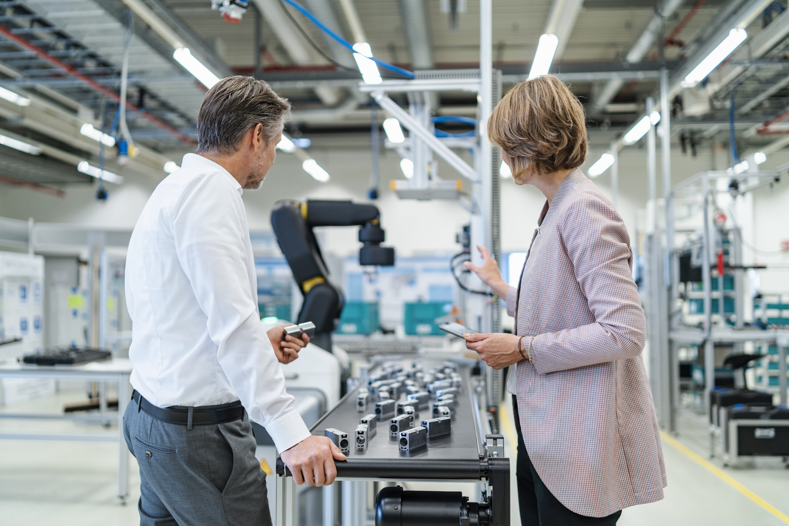 Businessman and businesswoman talking in a modern factory hall