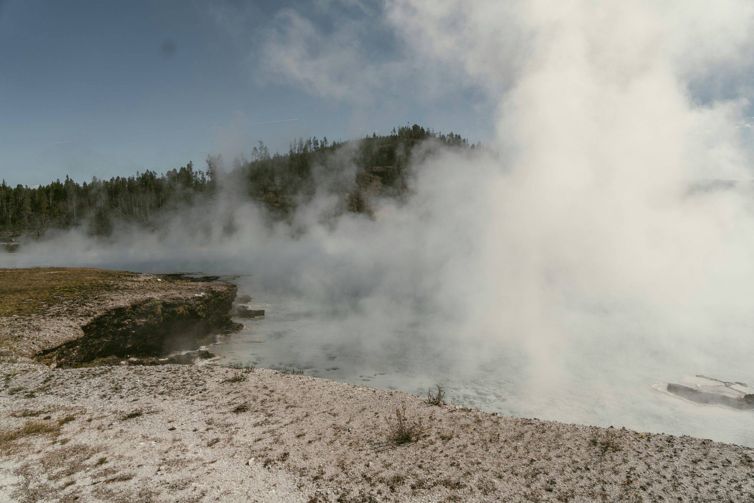 steam-rises-from-the-ground-near-a-body-of-water